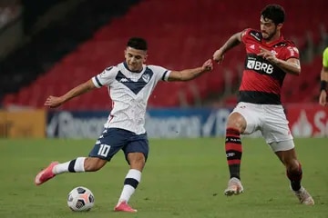 Thiago Almada, with the Vélez shirt, in front of the Flamengo defender Gustavo Henrique 