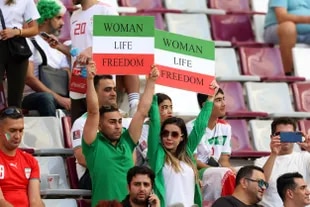 Iranian fans hold banners in favor of women's rights ahead of the match against England at the Khalifa International Stadium.